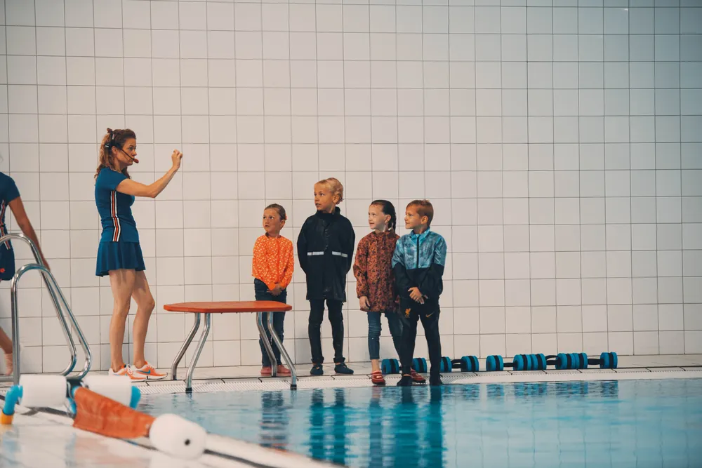 Kinderen luisteren naar de zweminstructrice