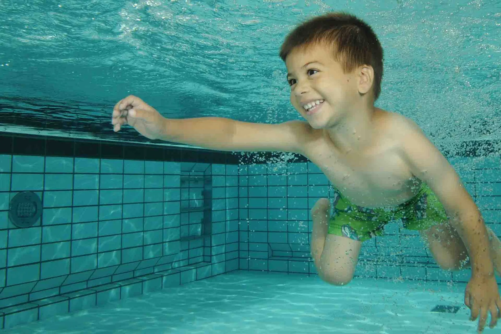 Jongen zwemt lachend onder water